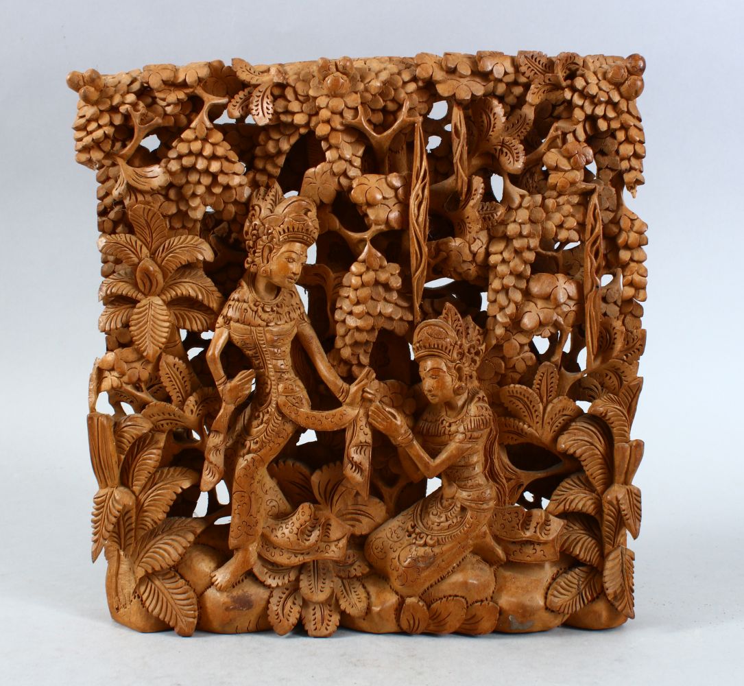 AN INDIAN CARVED RELIEF PANEL OF TWO FIGURES, the figures carved in relief around native foliage,