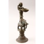 AN 18TH CENTURY INDIAN BRASS OIL LAMP, in the form of dipa lukshmi on an elephant, 24cm high x 8.5cm