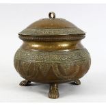 A EASTERN ANTIQUE BRONZE CIRCULAR POT & COVER, with embossed decoration, on three feet, 19cm high