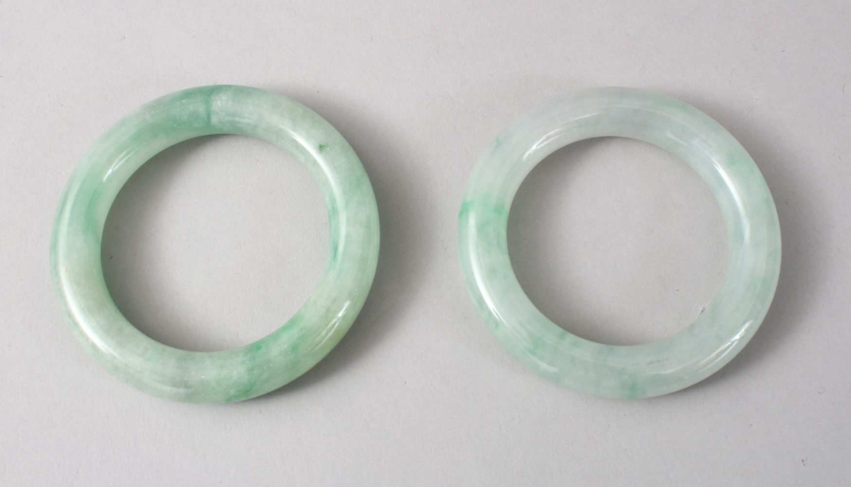 TWO GOOD CHINESE CARVED JADE BANGLES, 8cm diameter with an internal measurement of 5cm.