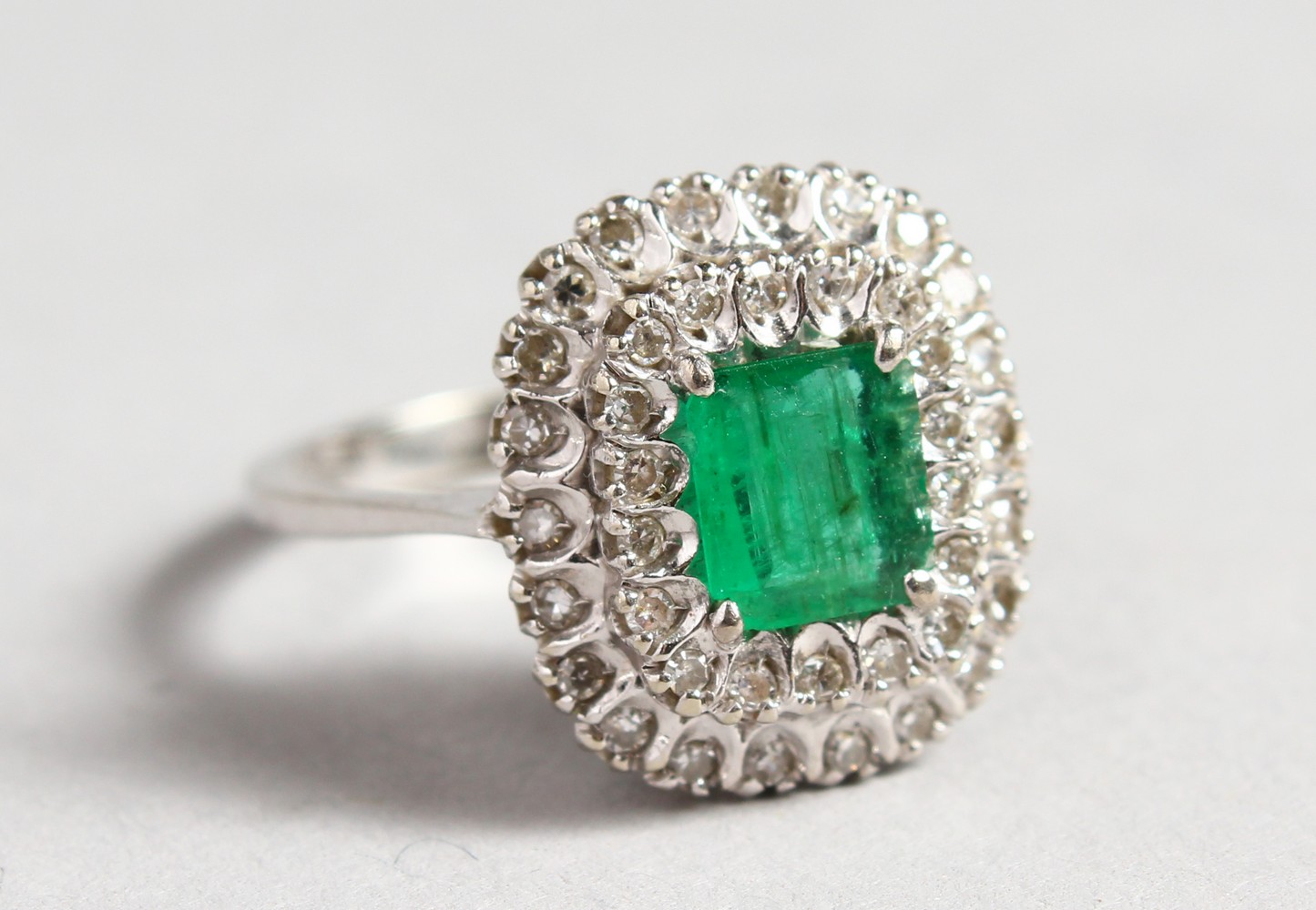 AN 18CT WHITE GOLD, DIAMOND AND EMERALD CLUSTER RING.