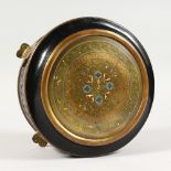 A 19TH CENTURY FRENCH EBONY AND BRASS CIRCULAR BOX, the hinged cover inlaid with enamel, on four