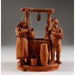 A TERRACOTTA GROUP OF TWO FIGURES STANDING BY A WELL. 6.5ins high.