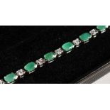 A SILVER EMERALD SET LINE BRACELET.