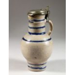 A FLEMISH SALT GLAZED POTTERY JUG, with pewter lid. 8ins high.