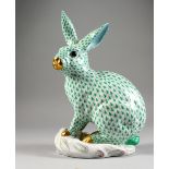 A HEREND LARGE PORCELAIN MODEL OF A RABBIT, seated on a moulded base. 12ins high.