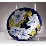 A GOOD MOORCROFT BLUE GROUND CIRCULAR BOWL, "Hibiscus". MOORCROFT. WM in green. 10.25ins diameter.