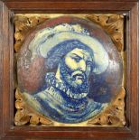 AN ITALIAN MAJOLICA TILE, depicting a man with a beard, wearing a hat, in an oak frame. 14ins wide.