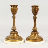 A SMALL PAIR OF ORMOLU CANDLESTICKS, on circular marble bases. 6.75ins high.