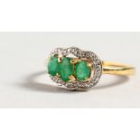 A 9CT GOLD THREE STONE EMERALD AND DIAMOND RING.