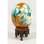 AN OSTRICH EGG DECORATED WITH AFRICAN ANIMALS, on a carved wood stand. 8.5ins high.