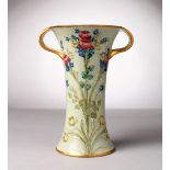 A MOORCROFT MACINTYRE POTTERY TWO-HANDLED VASE, green ground, edge in gilt with flowers. Script