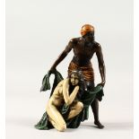 A PAINTED COLD CAST BRONZE OF AN ARAB SLAVER WITH A NAKED FEMALE SLAVE. 5.5ins high.