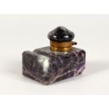 AN AMETHYST INKWELL, with hinged lid and pen rest. 2.75ins diameter.