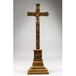 A WOODEN CRUCIFIX, with embossed white metal Corpus Christi and other emblems. 23ins high.