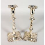 A PAIR OF 18TH CENTURY STYLE SILVER CANDLESTICKS, with shell cast sconces and knopped stems, on