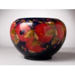 A LARGE MOORCROFT POTTERY CIRCULAR FRUIT BOWL, pomegranate on a blue ground. W. Moorcroft