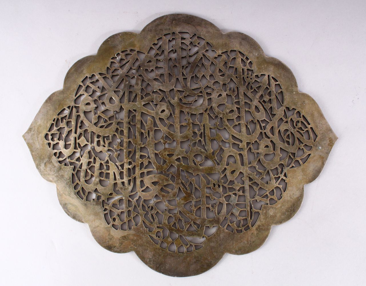 A FINE QUALITY ISLAMIC PERSIAN WHITE METAL PIERCED CALLIGRAPHIC WALL PANEL, 37CM X 31CM.