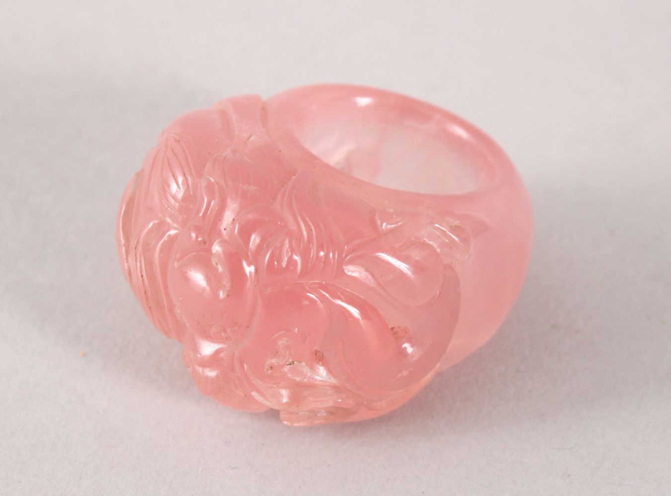 A GOOD CHINESE CARVED ROSE QUARTS DRAGON RING, the ring carved with a dragon upon flaming pearl,