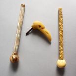 THREE DECORATIVE PARASOL HANDLES, one carved as a birds head. 6.25ins long and smaller.