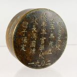 A CHINESE CIRCULAR BRONZE BOX, the cover with calligraphy. 2.75ins diameter.