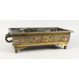 A CHINESE BRONZE RECTANGULAR CENSER, with mask handles, on scrolling feet. 17ins wide.