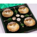 A SET OF FOUR VICTORIAN SHELL SHAPED SALTS AND SPOONS, in a fitted case. Birmingham 1876.