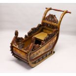 A CONTINENTAL CARVED AND PAINTED SLEIGH, each side decorated with mountainous river landscapes