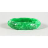 A CARVED CHINESE APPLE JADE BANGLE. 2.75ins diameter.
