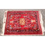 A 20TH CENTURY PERSIAN RUG, bright red ground with floral decoration. 5ft 3ins x 2ft 10ins.