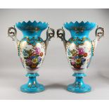 A PAIR OF SEVRES STYLE PORCELAIN TWIN-HANDLED PEDESTAL VASES, pale blue ground, decorated with