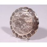 A CHINESE SILVER COMPACT, decorated with a figure in a landscape. 3.5ins diameter.