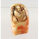 A SOAPSTONE SEAL, carved with a seated man. 2.5ins high.