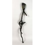 A FOLK ART WALKING STICK, carved as entwined snakes. 37ins long.