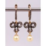 A PAIR OF 14CT YELLOW GOLD EARRINGS IN THE FORM OF BOWS, set with diamonds and pearl drops.