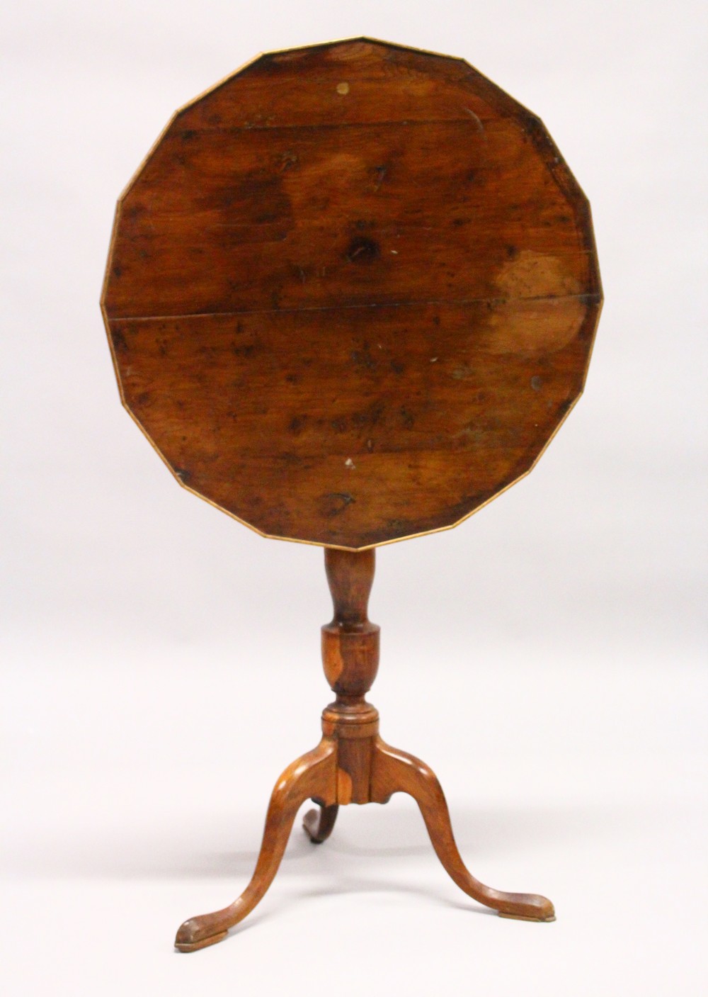 AN 18TH CENTURY YEW WOOD TILT TOP TRIPOD TABLE, with a shaped top, later edged, on a turned column