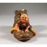 A CONTINENTAL PAINTED TERRACOTTA GROUP OF A MAN ON A SHOE. 5ins high.