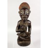A GOOD TRIBAL CARVED WOOD SEATED MATERNAL FIGURE. 15ins high.