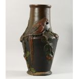 A CONTINENTAL PAINTED TERRACOTTA VASE, with moulded decoration of a parrot on a branch. 16ins high.