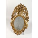 A 19TH CENTURY CARVED GILTWOOD MIRROR, with oval plate, the frame carved with a basket of flowers