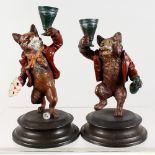 A PAIR OF BRONZE FOX AND BEAR CANDLESTICKS, on circular bases. 6.5ins high.