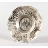 A CHINESE SHAPED SILVER DISH, with flowers and calligraphy. 4ins diameter.