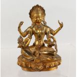 A CHINESE GILT BRONZE MULTI-ARM SEATED DEITY, inset with turquoise and coral. 7.5ins high.