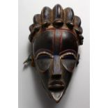 A GOOD CARVED WOOD TRIBAL MASK, with red and blue pigment. 11ins high.