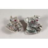 TWO SILVER DOG BROOCHES, set with rubies and emeralds.