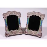 A PAIR OF SILVER AND ENAMEL ART NOUVEAU DESIGN UPRIGHT PHOTOGRAPH FRAMES, repousse with flowers