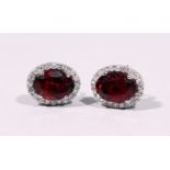 A PAIR OF 18CT WHITE GOLD, GARNET AND DIAMOND OVAL SHAPED STUD EARRINGS of 2.2cts.