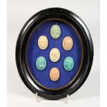 A SET OF SEVEN WAX PORTRAIT BUST SEALS, in an oval glazed frame. 10ins high.