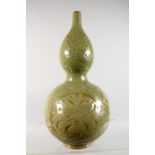 A CHINESE GREEN CELADON DOUBLE GOURD VASE, with incised decoration. 13ins high.