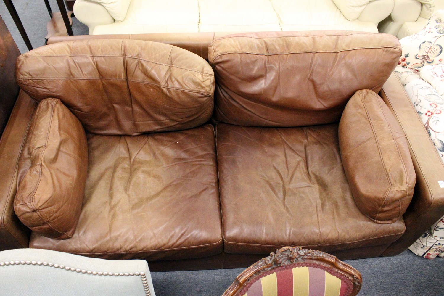 A modern brown leather two seater sofa.